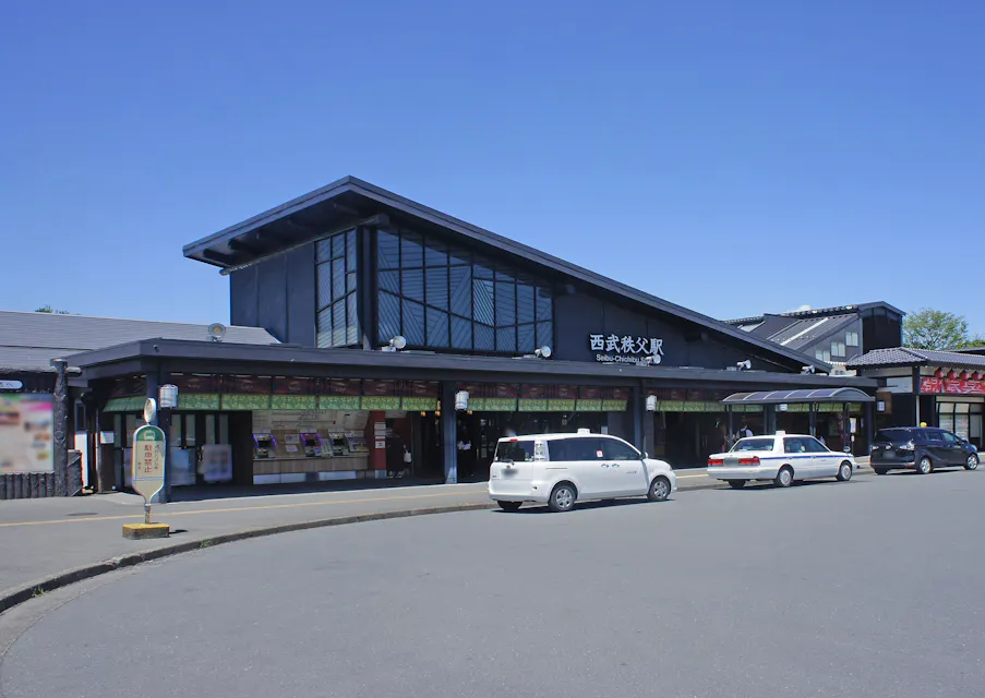 Seibu-Chichibu Station is the starting point for Chichibu's anime pilgrimage course. The modern wooden station building at Seibu-Chichibu Station under a clear blue sky