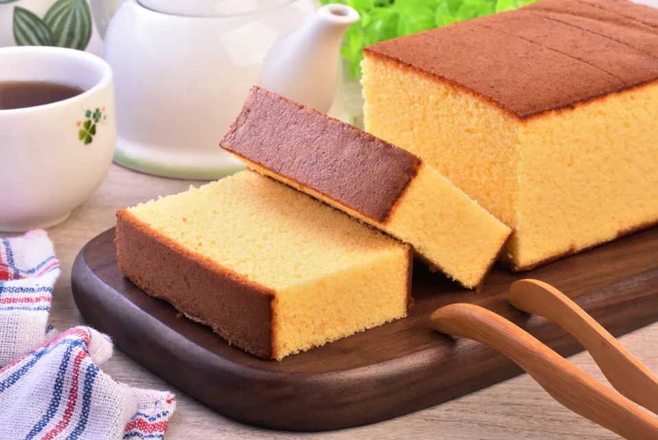 Castella (kasutera) - Delicious sliced sponge cake on wooden plate Castella (kasutera) - Delicious sliced sponge cake on wooden plate