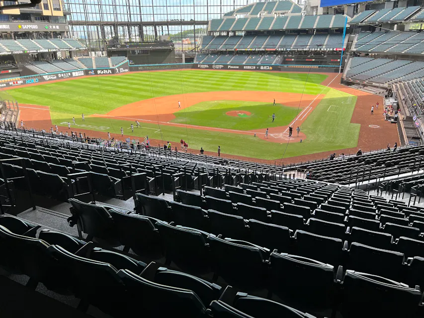 Daylight reaches the field through the glass outfield wall even when the roof is closed View of the Es Con Field playing surface from the seating bowl on a sunny afternoon with players warming up