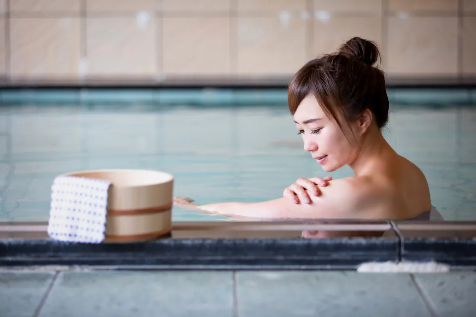 Private Kashikiri Onsen at a Japanese Ryokan A woman enjoying a private kashikiri onsen at a traditional Japanese ryokan, relaxing in a secluded indoor hot spring bath.