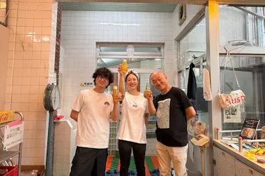 Guide and guest holding beer bottles in a retro Osaka bathhouse converted into a brewery
