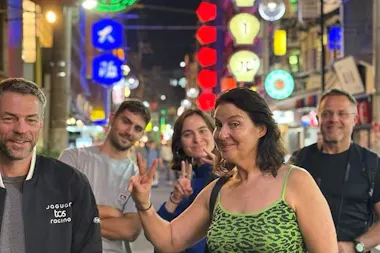 Tour group posing under glowing neon signs on a lively Namba street during an Osaka evening food tour