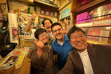 Selfie of a traveller with cheerful Osaka bar regulars giving thumbs up inside a retro Namba izakaya