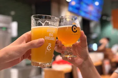Two hands clinking hazy pale ale and amber craft beer glasses at an Osaka craft beer bar