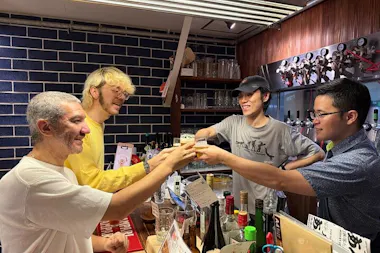 Four people toasting craft beer tasting glasses across a bar counter in Osaka