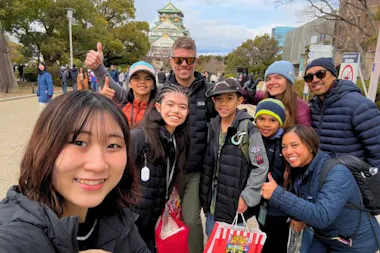 Tour group giving a thumbs up in front of Osaka Castle on a winter day during the highlights walking tour