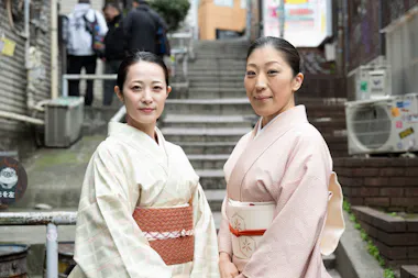 Two geisha in kimono posing together on a Shibuya backstreet in Tokyo before a private show