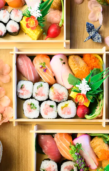 Colorful bento boxes from a small-group sushi class Several handmade sushi bento boxes arranged with cherry blossoms and temari balls, seen from above