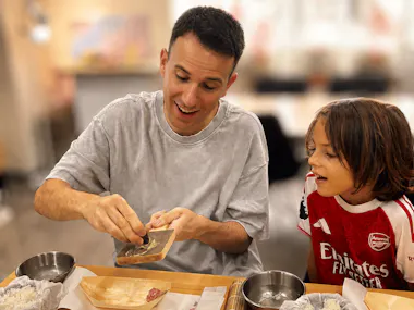 An instructor grating fresh wasabi as a young boy watches at a Tsukiji sushi class