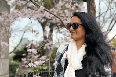 Close-up of a traveler beside delicate pink cherry blossom branches on an Osaka hanami tour