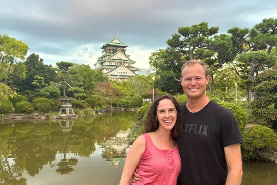 Couple posing across a garden pond from Osaka Castle during a walking tour in Osaka