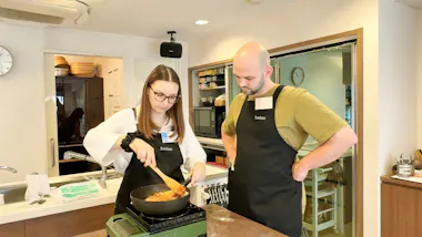 Two guests cooking chicken fried rice on a portable stove in a Tokyo kitchen studio