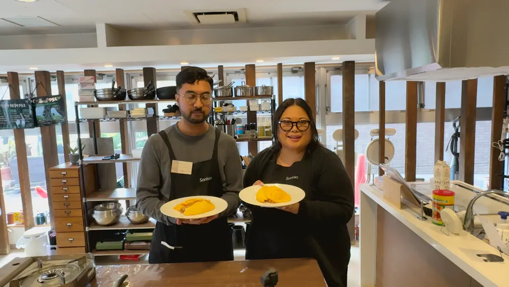 Two cooks with their finished omurice. Two guests holding plates of omurice in a cooking studio in Ebisu, Tokyo