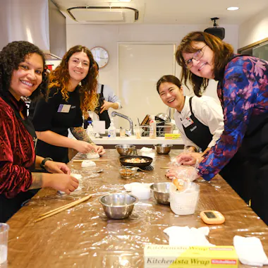 Shaping rice balls around the counter. Group of guests shaping onigiri around a long kitchen counter in Ebisu
