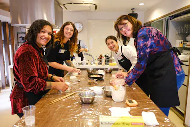 Group of guests shaping onigiri around a long kitchen counter in Ebisu