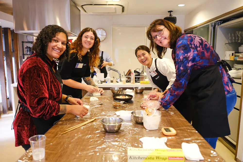 Shaping rice balls around the counter. Group of guests shaping onigiri around a long kitchen counter in Ebisu