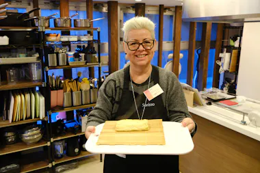 Guest holding a freshly made tamagoyaki rolled omelet on a bamboo mat
