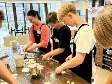 Group of travelers preparing gyoza wrappers together at a Tokyo cooking class