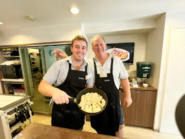 Two guests holding a frying pan of freshly cooked gyoza in a cooking studio