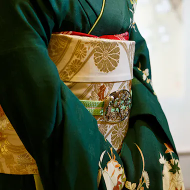 Detail of a maiko's kimono and obi. Close-up of a maiko's green kimono and gold brocade obi with a decorative clasp