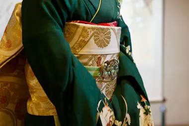Close-up of a maiko's green kimono and gold brocade obi with a decorative clasp