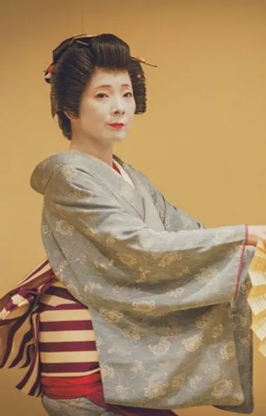 A geisha dances with a fan in the tea house. Asakusa geisha dancing with a folding fan beside a woman in dark kimono in a tatami room
