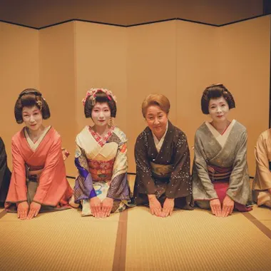 A warm welcome from the okami and geisha. Okami and geisha kneeling in a row to welcome guests in a tatami room
