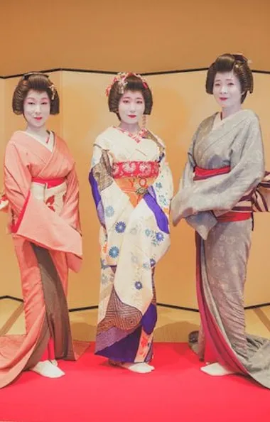 Three geisha in elegant, colorful kimono. Three geisha in colorful kimono standing before a gold folding screen