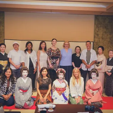 A group photo with the geisha to close the session. Group of guests posing with geisha in a tatami hall at an Asakusa tea house