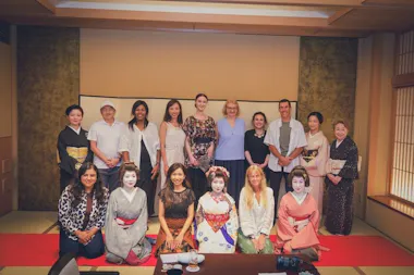 Group of guests posing with geisha in a tatami hall at an Asakusa tea house