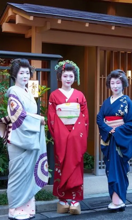 Geisha in front of the historic Miyakodori tea house in Asakusa. Three Asakusa geisha in kimono standing at the entrance of the Miyakodori tea house