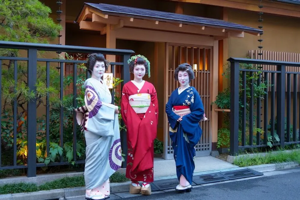 Three Asakusa geisha in kimono standing at the entrance of the Miyakodori tea house