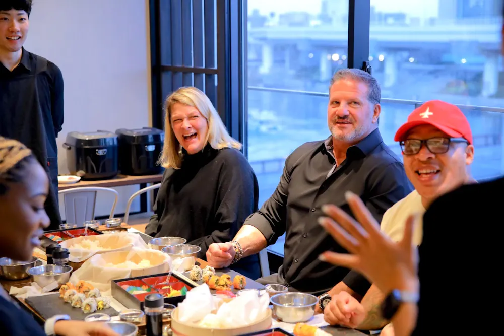 Group sharing jokes around a table full of sushi trays