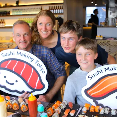 A family group's sushi spread. Family holding sushi mascot signs over a table of homemade rolls