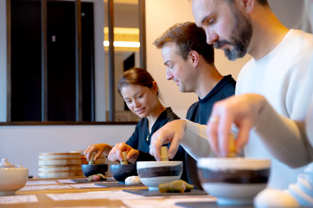 Whisking side by side in Asakusa. Group whisking matcha in tea bowls at a long table in Asakusa