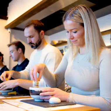 Measuring matcha with the chashaku. Group preparing matcha powder with bamboo scoops