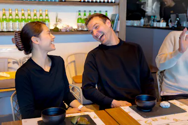 Couple laughing together at a matcha table with tea bowls