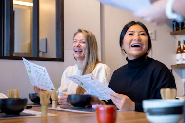 Two women laughing as they read about matcha at the table