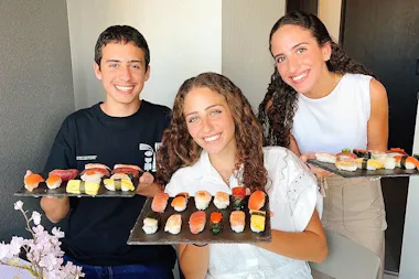 Three friends proudly holding trays of homemade nigiri