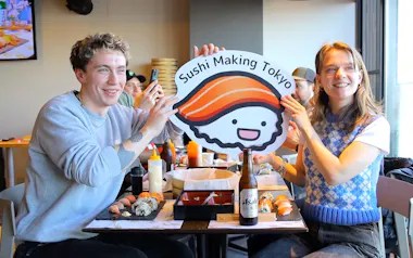 Travelers holding a Sushi Making Tokyo sign beside their finished sushi in Asakusa