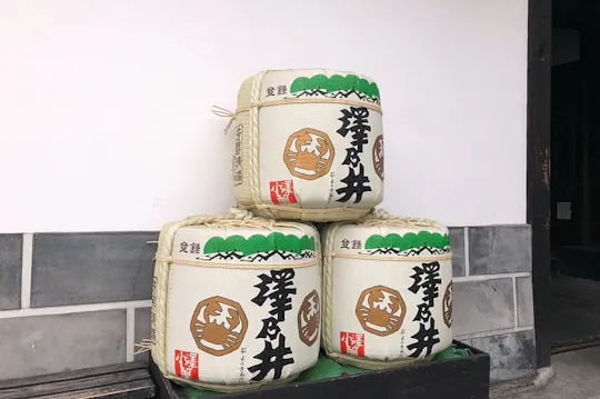 Stacked straw-wrapped Sawanoi sake barrels at the brewery