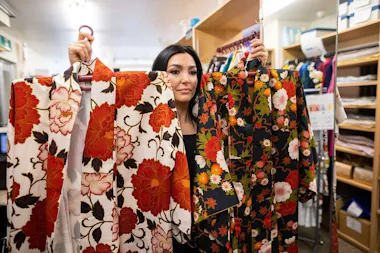 Staff holding up colorful kimono for a guest to choose