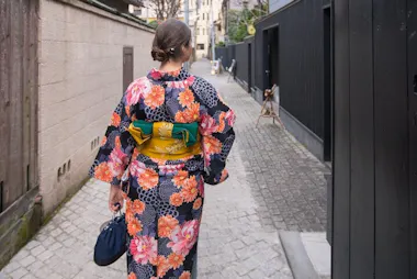 Woman in kimono walking away down a stone-paved alley