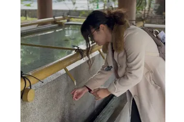 Guest rinsing her hands at a shrine water basin
