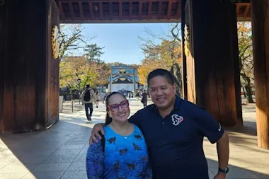 Couple posing under a large wooden shrine gate at Yasukuni