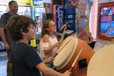Children playing a Taiko no Tatsujin drum game at an arcade