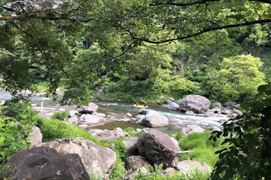 Clear Tama River flowing past boulders in a green valley
