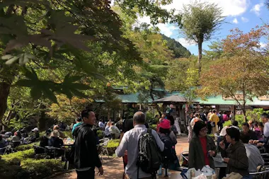 Visitors relaxing at tables in a riverside sake brewery garden