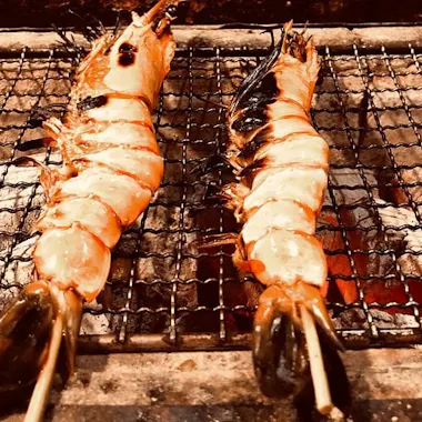 Tiger prawns over charcoal. Two tiger prawns roasting over a charcoal grill