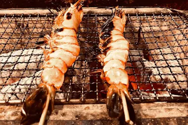 Two tiger prawns roasting over a charcoal grill